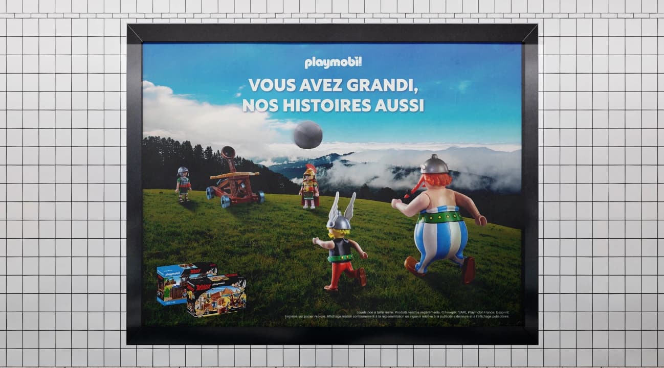 Affiche Playmobil « Vous avez grandi, nos histoires aussi » dans un couloir de métro carrelé de blanc.